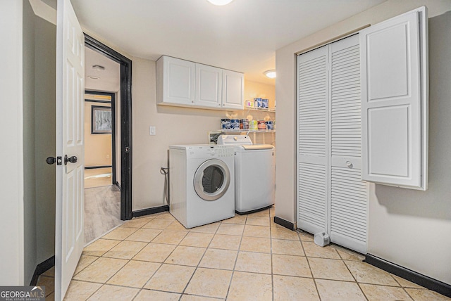 laundry room with washer and dryer, light tile patterned floors, and cabinets