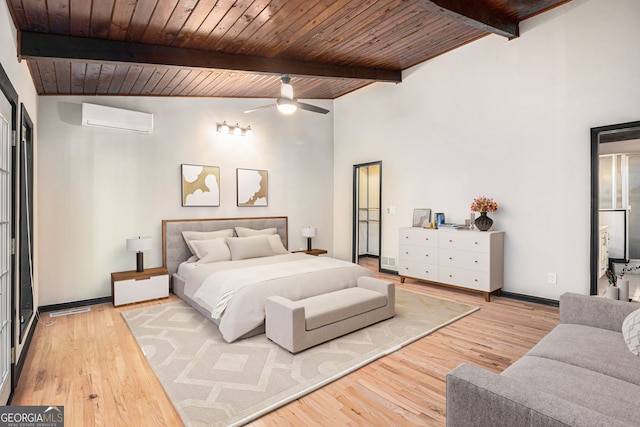 bedroom with a wall unit AC, beamed ceiling, wood ceiling, and light hardwood / wood-style floors