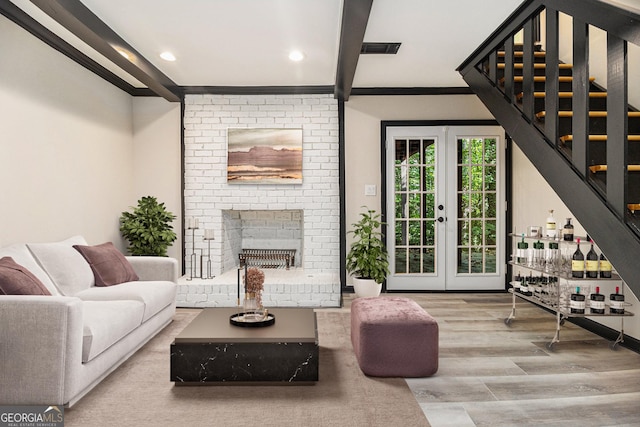 living room featuring french doors, a fireplace, crown molding, wood-type flooring, and beamed ceiling