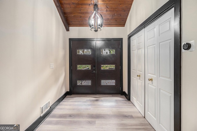 entryway featuring french doors, light hardwood / wood-style floors, an inviting chandelier, and wooden ceiling