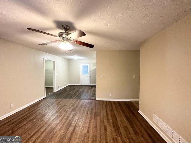 spare room with dark hardwood / wood-style floors, ceiling fan, and a textured ceiling