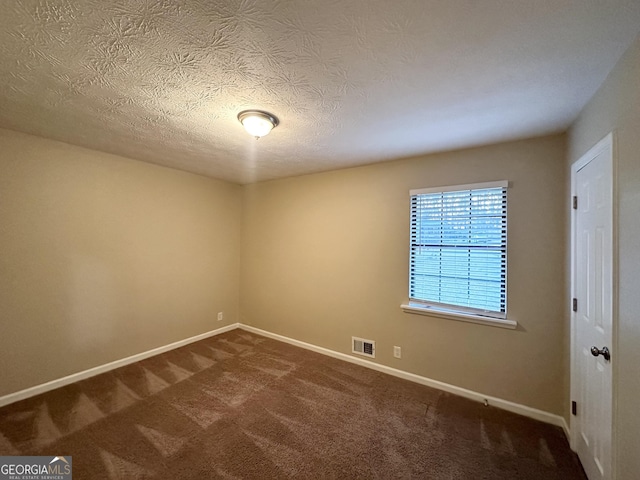 empty room featuring dark colored carpet and a textured ceiling