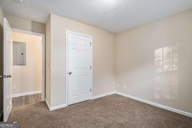 unfurnished bedroom featuring electric panel, a closet, carpet floors, and a textured ceiling