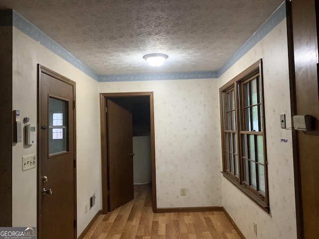 hallway with light wood-type flooring and a textured ceiling