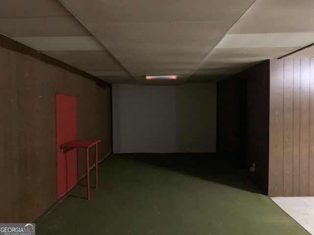 basement with wood walls and golf simulator