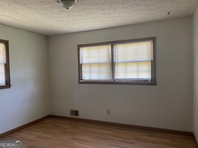 unfurnished room with wood-type flooring and a textured ceiling