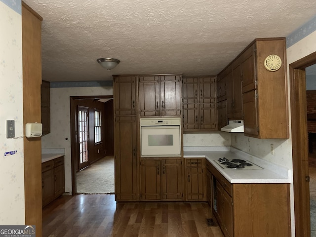 kitchen with a textured ceiling, dark hardwood / wood-style floors, and white appliances