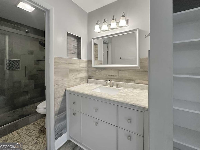 bathroom featuring tiled shower, vanity, tile walls, and toilet