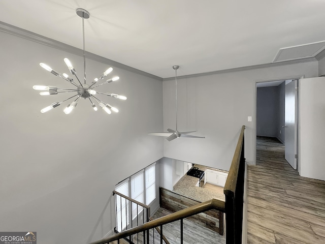 stairway featuring crown molding, ceiling fan with notable chandelier, and hardwood / wood-style flooring