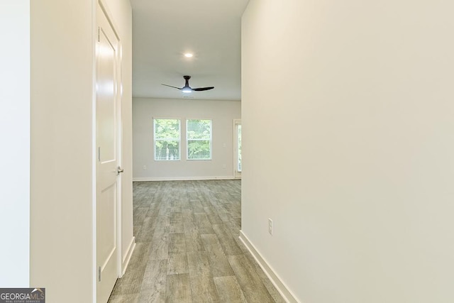 corridor featuring light wood-type flooring and baseboards