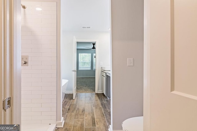 bathroom featuring vanity, ceiling fan, toilet, and tiled shower