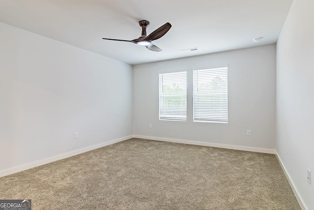 carpeted empty room featuring a ceiling fan and baseboards