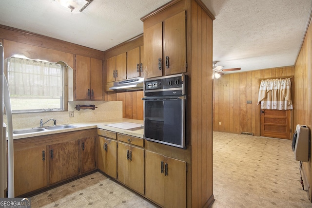1228 Old Rockmart Rd SE, Silver Creek, GA 30173 - kitchen featuring black oven, a sink, under cabinet range hood, light flooring, and brown cabinetry