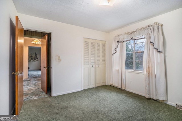 unfurnished bedroom with a textured ceiling, dark carpet, and a closet