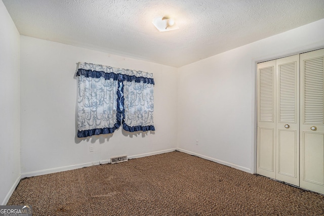 unfurnished bedroom with carpet flooring, a textured ceiling, and a closet