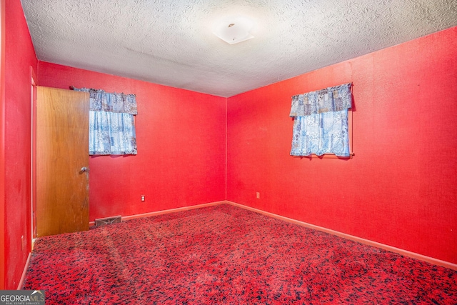 carpeted empty room featuring a textured ceiling