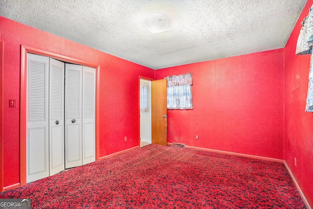 unfurnished bedroom featuring carpet flooring, a textured ceiling, and a closet