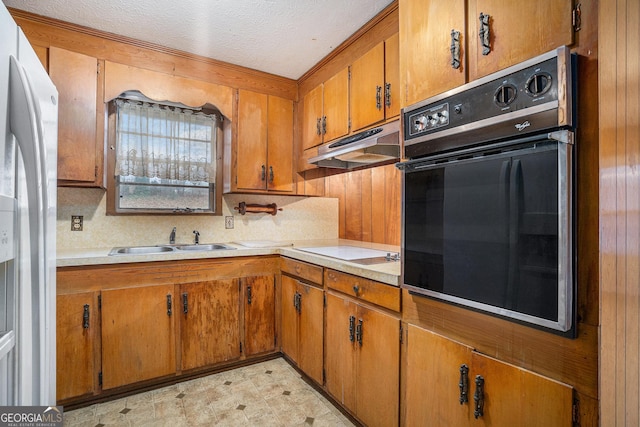 kitchen with sink, cooktop, white refrigerator with ice dispenser, oven, and a textured ceiling