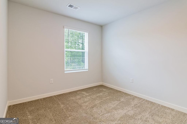 spare room with carpet, visible vents, and baseboards