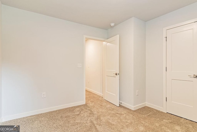 unfurnished bedroom featuring light carpet and baseboards