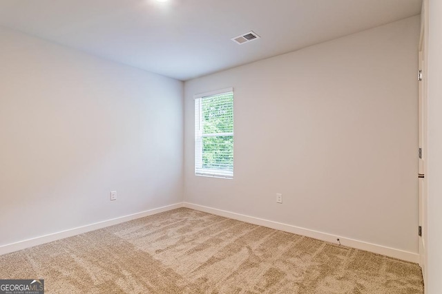 empty room featuring baseboards, visible vents, and light colored carpet