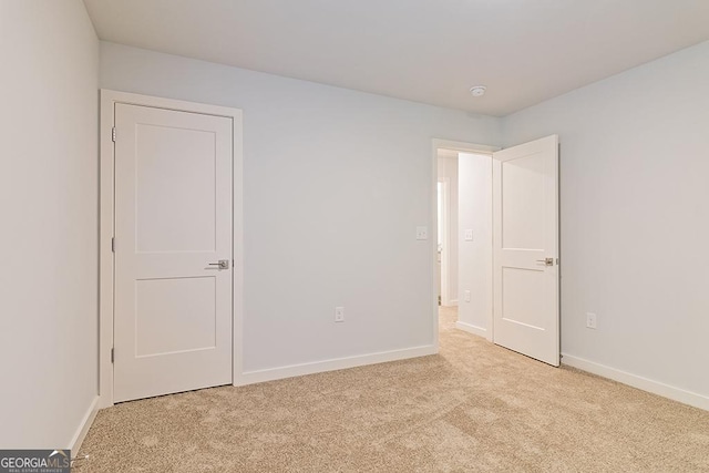 unfurnished bedroom with light colored carpet and baseboards