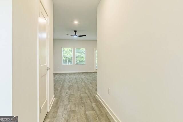 kitchen featuring hardwood / wood-style floors, an island with sink, pendant lighting, ceiling fan with notable chandelier, and appliances with stainless steel finishes