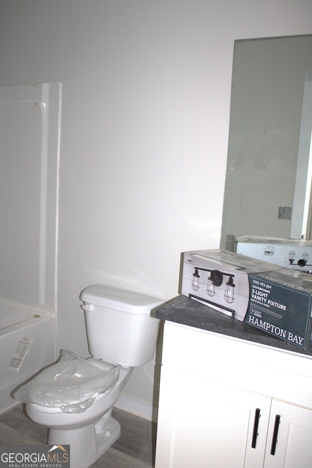 bathroom featuring a bathing tub, hardwood / wood-style floors, vanity, and toilet