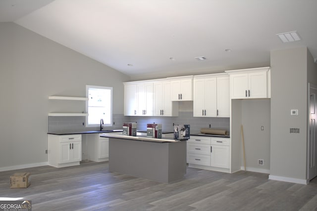 kitchen with light wood-type flooring, a center island, white cabinetry, and lofted ceiling