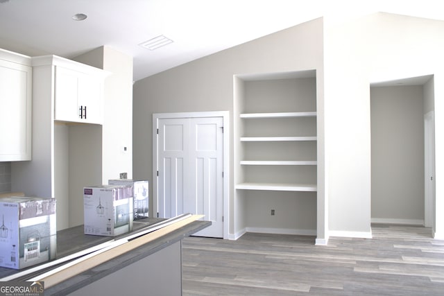 kitchen featuring lofted ceiling, dark hardwood / wood-style flooring, and white cabinetry