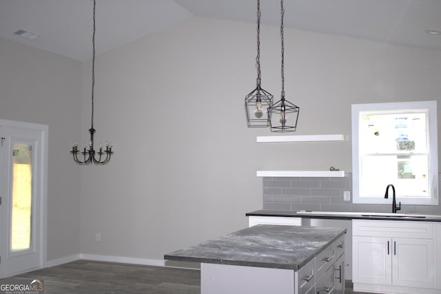 kitchen with a wealth of natural light, white cabinets, decorative light fixtures, and a kitchen island