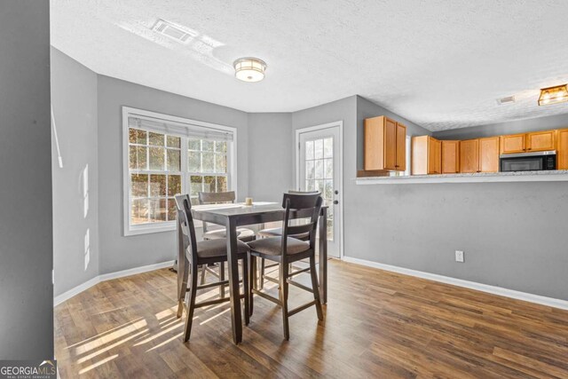 dining room featuring a textured ceiling and dark hardwood / wood-style flooring