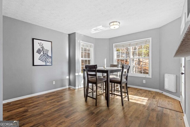 dining area with a textured ceiling and dark wood-type flooring