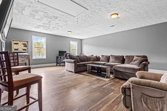 living room with a textured ceiling and dark hardwood / wood-style floors