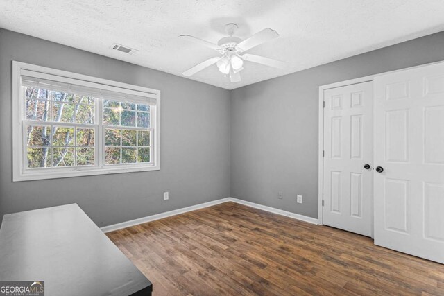 bedroom featuring a textured ceiling, ceiling fan, a closet, and dark hardwood / wood-style floors