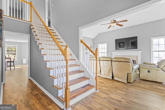 staircase featuring hardwood / wood-style flooring, ceiling fan, and vaulted ceiling