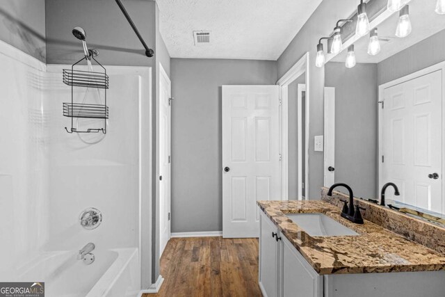 bathroom with shower / washtub combination, vanity, a textured ceiling, and hardwood / wood-style flooring