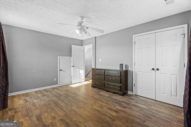 unfurnished bedroom with ceiling fan, dark hardwood / wood-style floors, a textured ceiling, and a closet