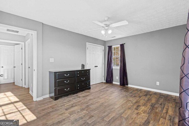 unfurnished bedroom with a textured ceiling, a closet, dark hardwood / wood-style floors, and ceiling fan