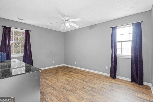 empty room with hardwood / wood-style flooring, ceiling fan, and a textured ceiling