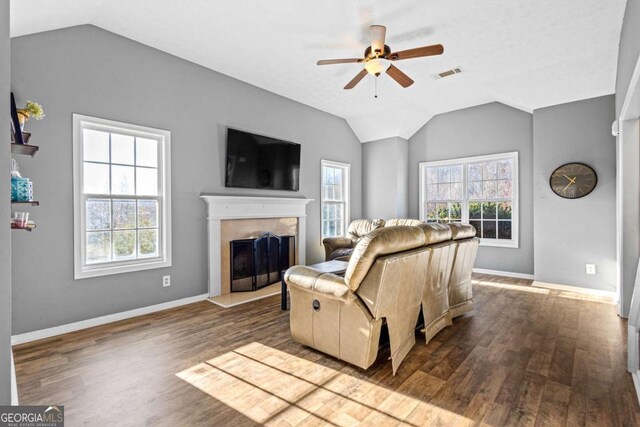 living room with hardwood / wood-style floors, ceiling fan, a tile fireplace, and vaulted ceiling