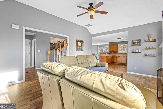 living room featuring light wood-type flooring, vaulted ceiling, ceiling fan, and sink