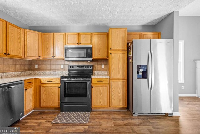 kitchen featuring dark hardwood / wood-style flooring, a textured ceiling, appliances with stainless steel finishes, and tasteful backsplash