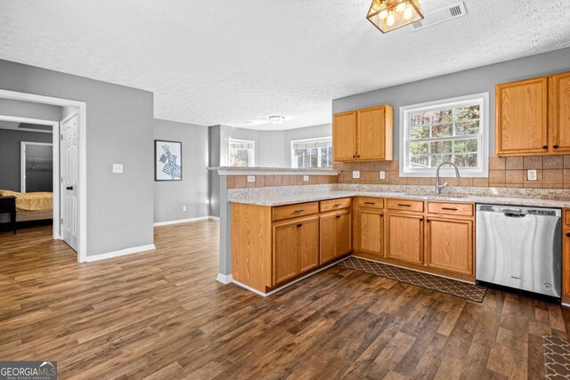 kitchen with dishwasher, sink, a textured ceiling, dark hardwood / wood-style flooring, and kitchen peninsula