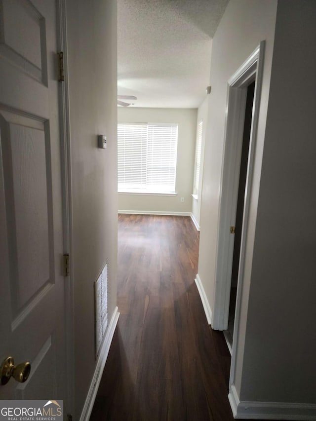 hallway with dark wood-type flooring and a textured ceiling