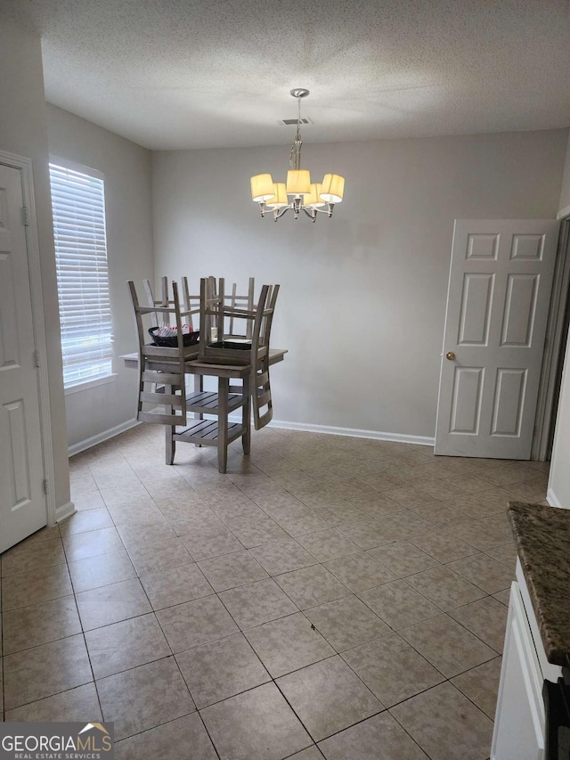 dining area featuring a notable chandelier, light tile patterned floors, and a textured ceiling