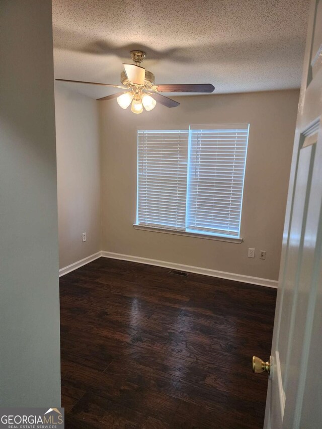 empty room featuring a textured ceiling, dark hardwood / wood-style floors, and ceiling fan