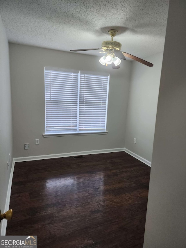 spare room with dark hardwood / wood-style floors, ceiling fan, and a textured ceiling