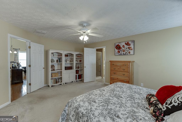 bedroom featuring a textured ceiling, light colored carpet, and ceiling fan