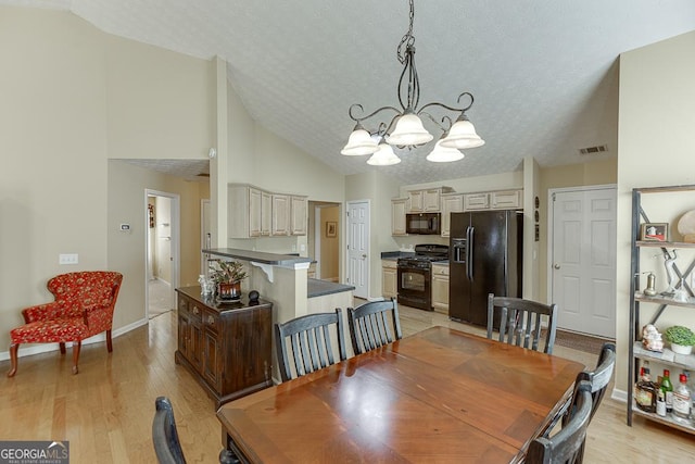 dining space featuring light hardwood / wood-style flooring, high vaulted ceiling, a textured ceiling, and an inviting chandelier